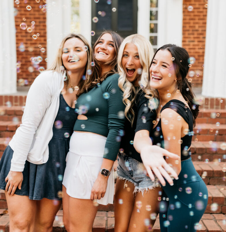 UGA college girls smiling and laughing with bubbles on sorority row in Athens, Georgia.