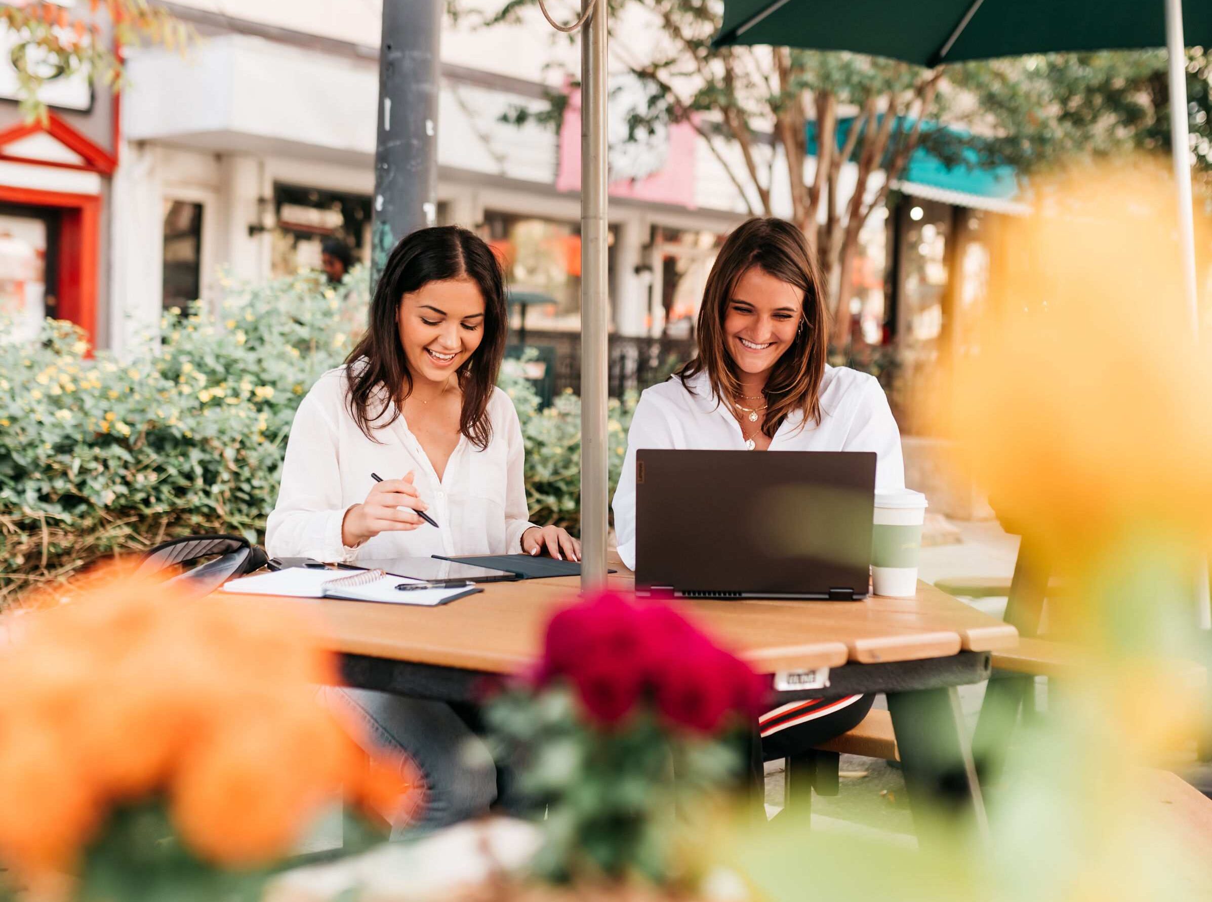 Two students sit at a picnic table in Athens and make a list of the questions they plan to ask when touring a student housing apartment near UGA