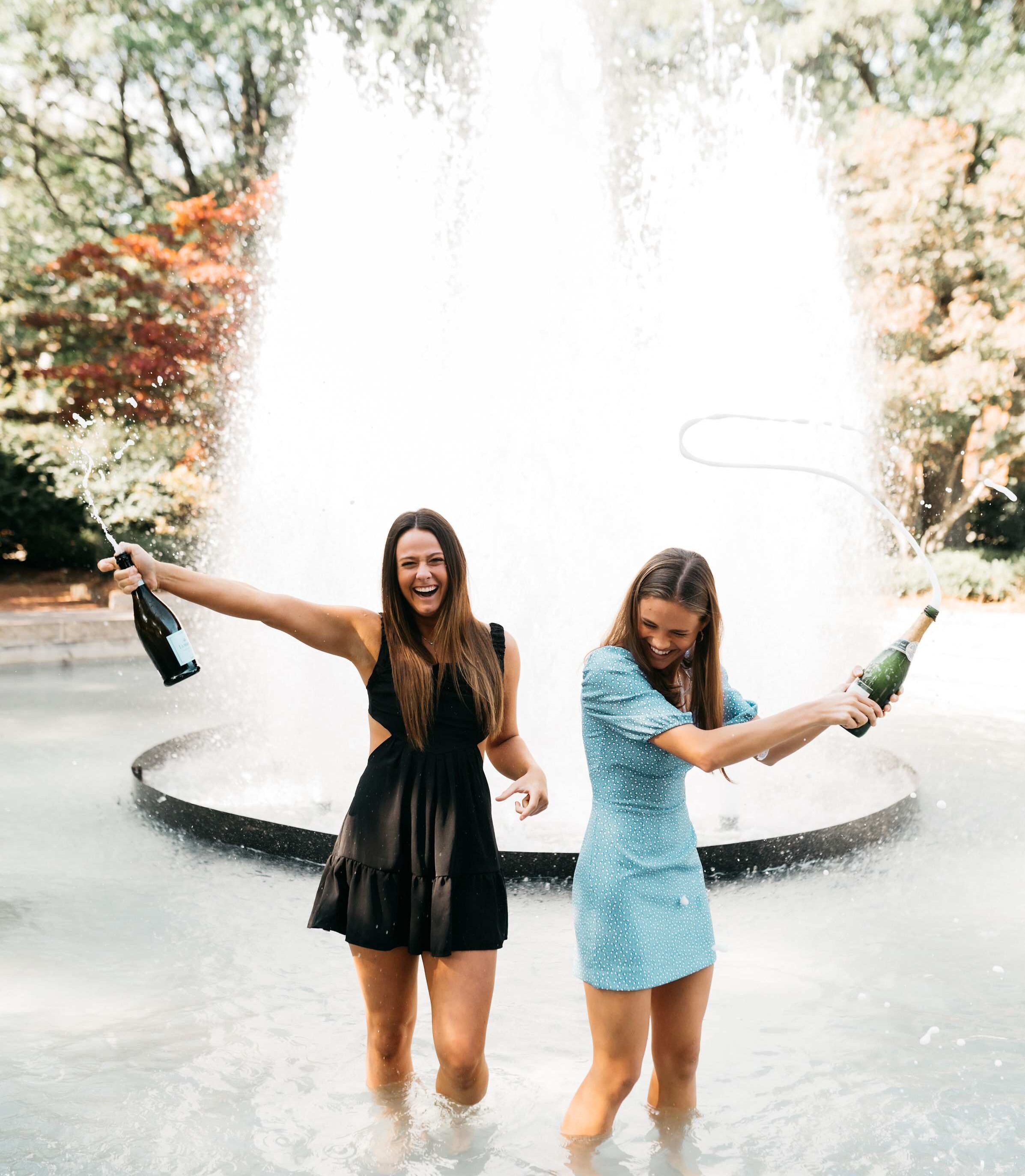 Two girls pop champagne in the fountain to celebrate graduating from the University of Georgia in Athens.