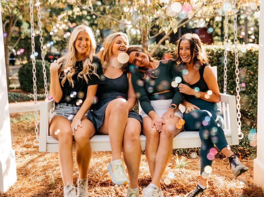 Girls laughing on bench outside of sorority house in Athens, GA