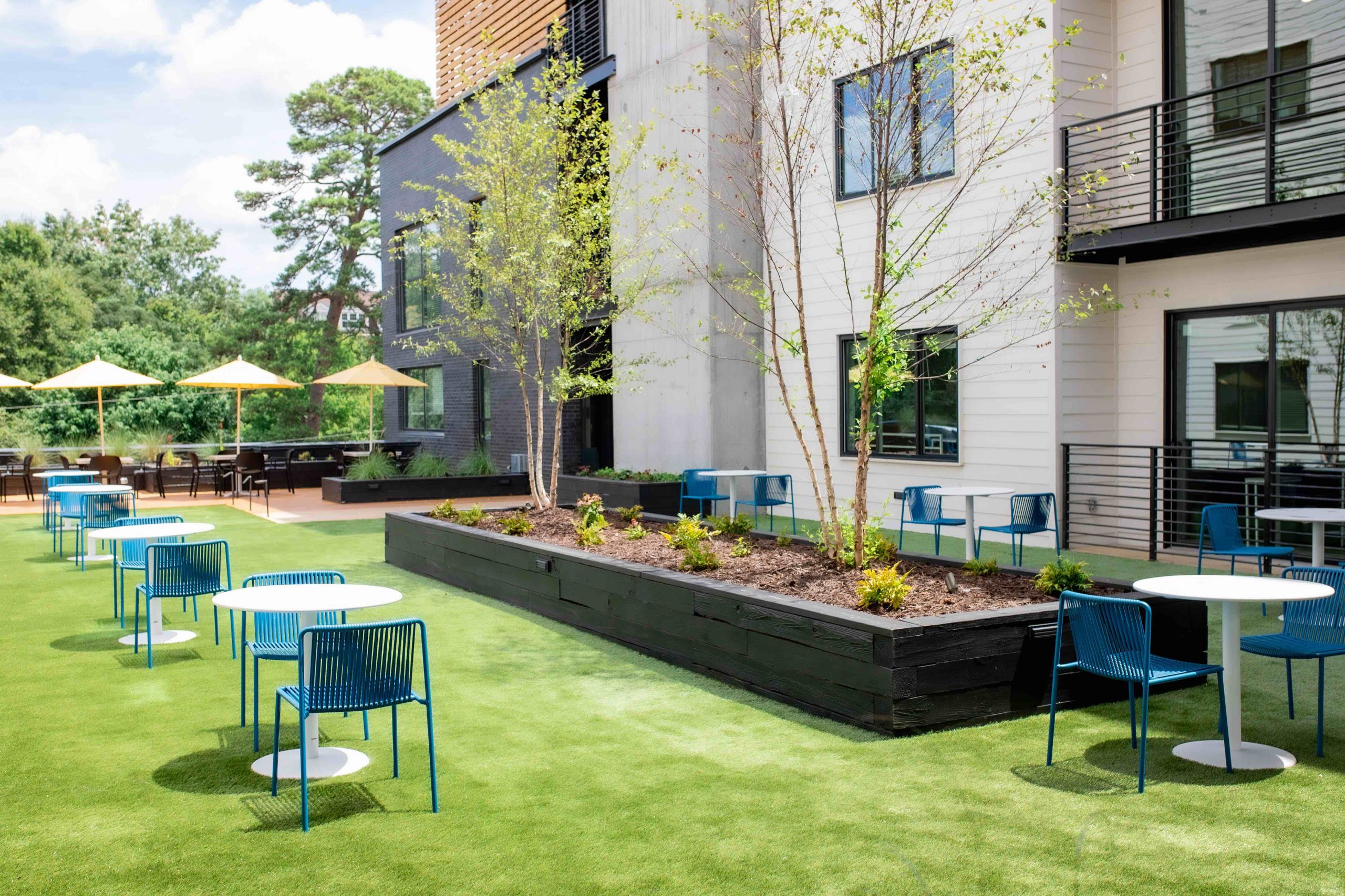 Wright House Athens courtyard terrace featuring tables, turf, and large planters