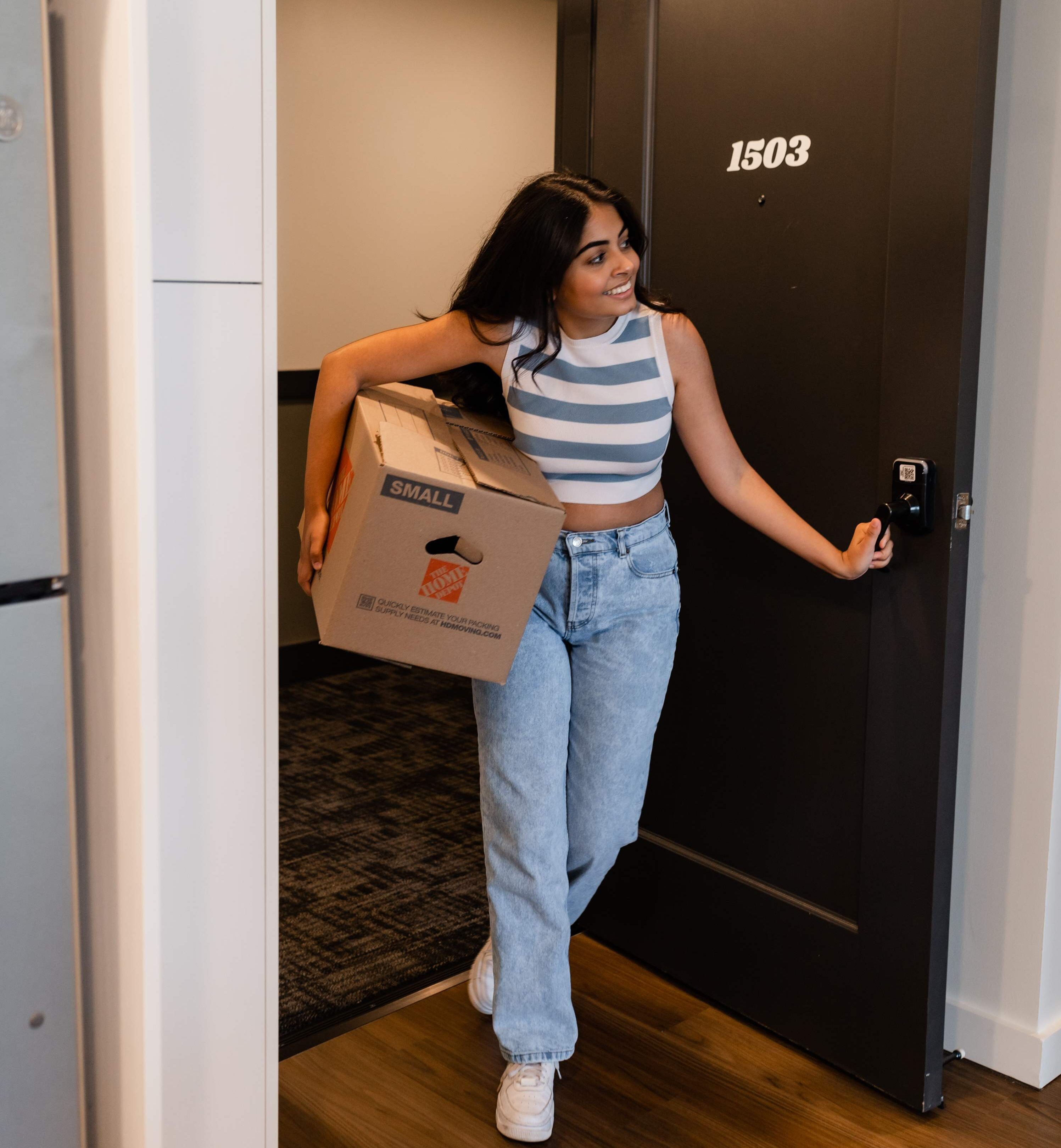 Woman with a moving box walking through the door
